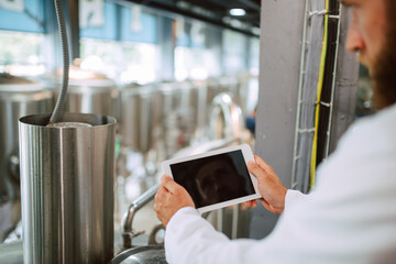 Closeup of tablet computer in hand of professional caucasian technologist expert in white uniform  in production plant - food or drink factory