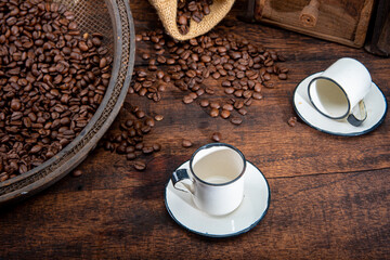 Roasted coffee on rustic wood, cup, grinder and more with black background, selective focus