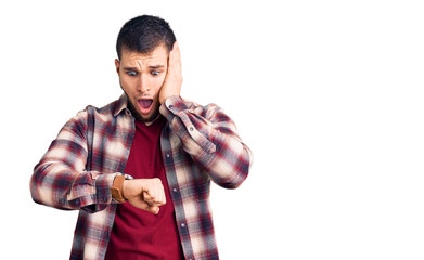 Young handsome man wearing casual shirt looking at the watch time worried, afraid of getting late