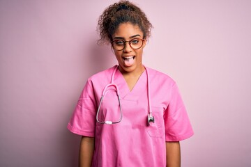 African american nurse girl wearing medical uniform and stethoscope over pink background sticking...