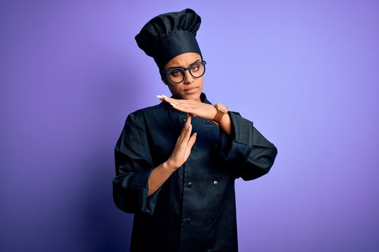 Young african american chef girl wearing cooker uniform and hat over purple background Doing time out gesture with hands, frustrated and serious face - Powered by Adobe