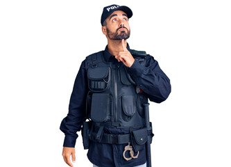 Young hispanic man wearing police uniform thinking concentrated about doubt with finger on chin and...