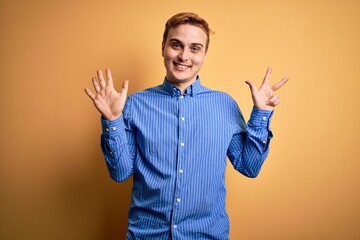 Young handsome redhead man wearing casual striped shirt over isolated yellow background showing and pointing up with fingers number eight while smiling confident and happy.