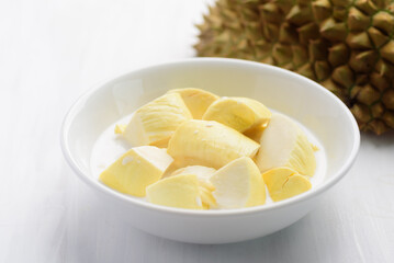 Thai dessert, sliced durian fruit with coconut milk in a bowl on white table background