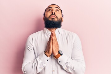 Young arab man wearing casual clothes begging and praying with hands together with hope expression on face very emotional and worried. begging.