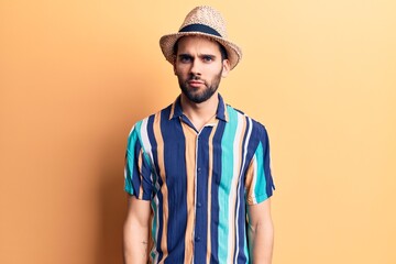 Young handsome man with beard wearing summer hat and shirt skeptic and nervous, frowning upset...