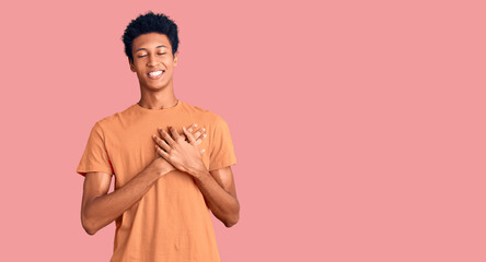 Young african american man wearing casual clothes smiling with hands on chest with closed eyes and grateful gesture on face. health concept.