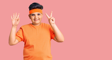 Little boy kid wearing sportswear showing and pointing up with fingers number seven while smiling confident and happy.