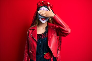 Woman wearing day of the dead costume over red smiling and laughing with hand on face covering eyes for surprise. blind concept.