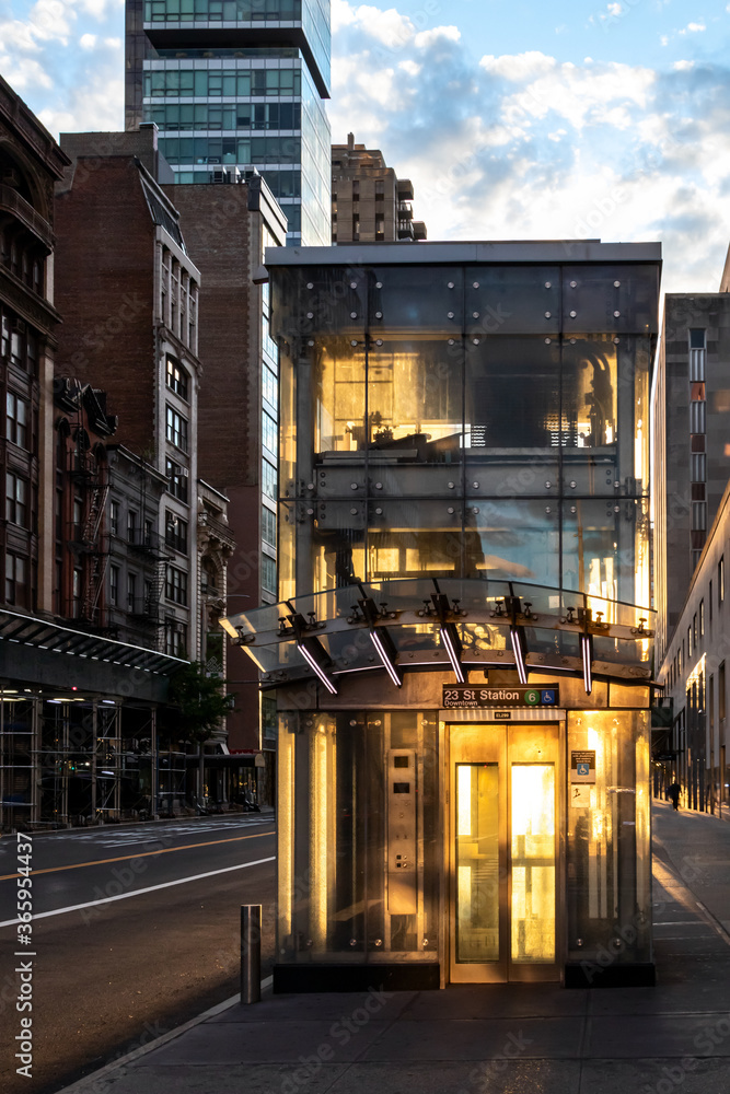 Wall mural new york city subway station elevator is glowing with the light of sunset shining through glass pane