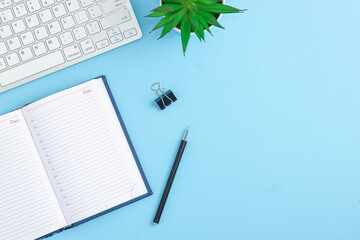 Office desk table with blank notebook, computer, supplies and coffee cup