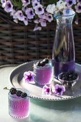 Blackberry mocktails with blackberry skewers ready for drinking on a bright sunlit table.