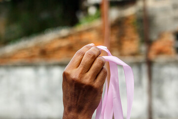 hand of a black woman holding a pink ribbon making champagne for the prevention of breast cancer in...