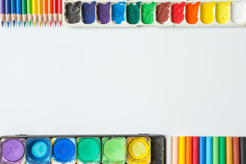 Top view of Colorful Watercolor palette, paintbrush, colored pencils and drawing equipment  on white background and copy space