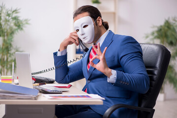 Male employee with mask in hipocrisy concept