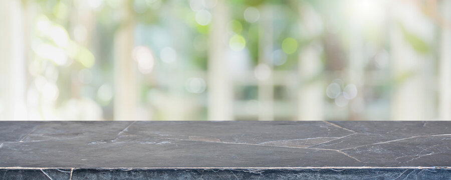 Empty black stone marble table top and blurred of interior restaurant with window view green from tree garden background background - can used for display or montage your products.