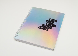 a notebook with iridiscent cover and motivational text, white background