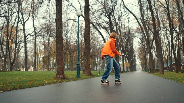 Smiling and happy bearded man enjoys roller skating, makes various technical turns and feints in the alley of Gorky Park, Kharkov, Ukraine. Experienced skater spends sports and active leisure outside.