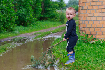 .Child in rubber boots playing in a puddle