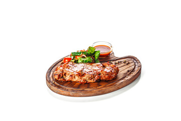 Juicy appetizing grilled steak served with a salad of tomato and green leaves and with red sauce. Food served on a wooden board. Isolated