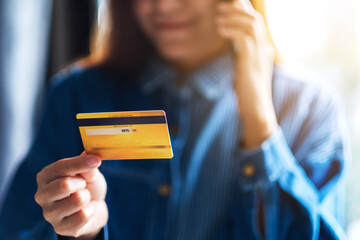 Closeup image of a young woman using credit card for purchasing and shopping online on mobile phone