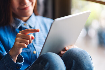 Closeup image of a beautiful young woman holding and using tablet pc
