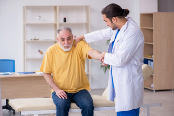Obraz premium Old injured man visiting young male doctor chiropractor