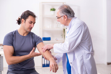 Obraz premium Young male patient visiting old doctor traumatologist