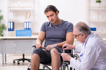 Young male patient in wheel-chair visiting old doctor