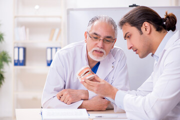 Experienced doctor dentist teaching young male assistant