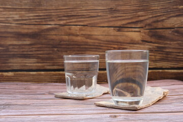 Pouring drinking water in glasses on wood table background and space for text