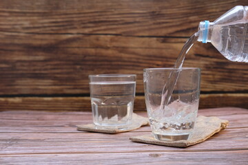 pouring water into glass on wood table 