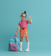Kid with backpack on color background.