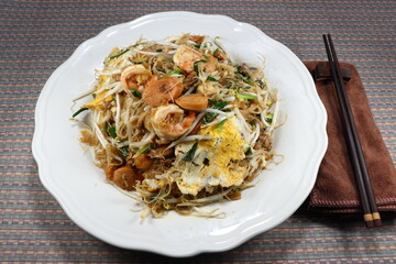 Traditional fried and stirred rice vermicelli with fresh bean sprouts, cutting spring onions, peeled shrimp, sliced pork sausage and egg on the plate. Famous special street food menu in Thailand. 