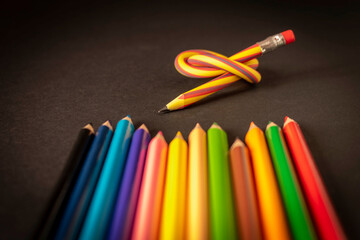 Flexible pencil and a set of colored pencils on a dark background. Selective focus.