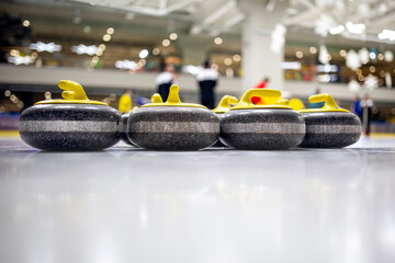 The curling stone or rock is made of granite with yellow handles lie