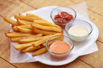 Tasty french fries on wooden table background