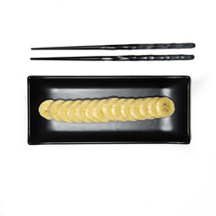 black plate and chopsticks with a banana