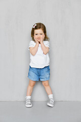 Two years old girl in t-short and jeans shorts posing in studio