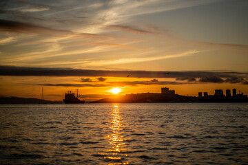 Naklejka premium Seascape with a view of the silhouette of the city and the ship