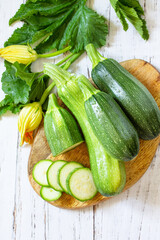 Fresh healthy uncooked green zucchini on a wooden kitchen table. Diet menu concept. Top view flat lay background.
