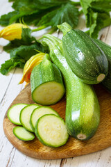 Fresh healthy uncooked green zucchini on a wooden kitchen table. Diet menu concept.