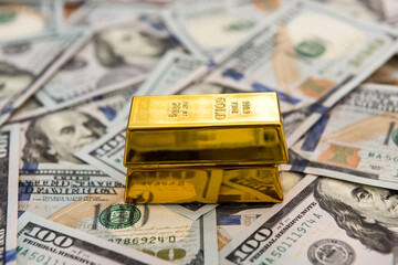 gold bars lying on dollar bills