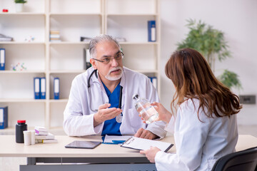 Fototapeta premium Old male doctor and his young female assistant in the clinic