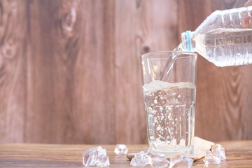 pouring water into glass on wood table 