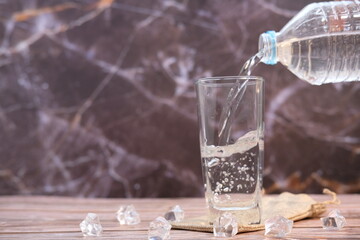 Pouring drinking water in glasses on wood table background and space for text