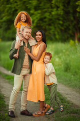 Happy international family on a summer walk in the park.