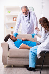 Obraz premium Two doctors visiting sick young man at home