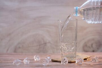 Pouring drinking water in glasses on wood table background and space for text
