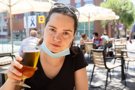 Woman Wearing Protective Face Mask Enjoying Beer Sitting At Outdoor Bar Terrace. Easing Coronavirus Lockdown Concept..